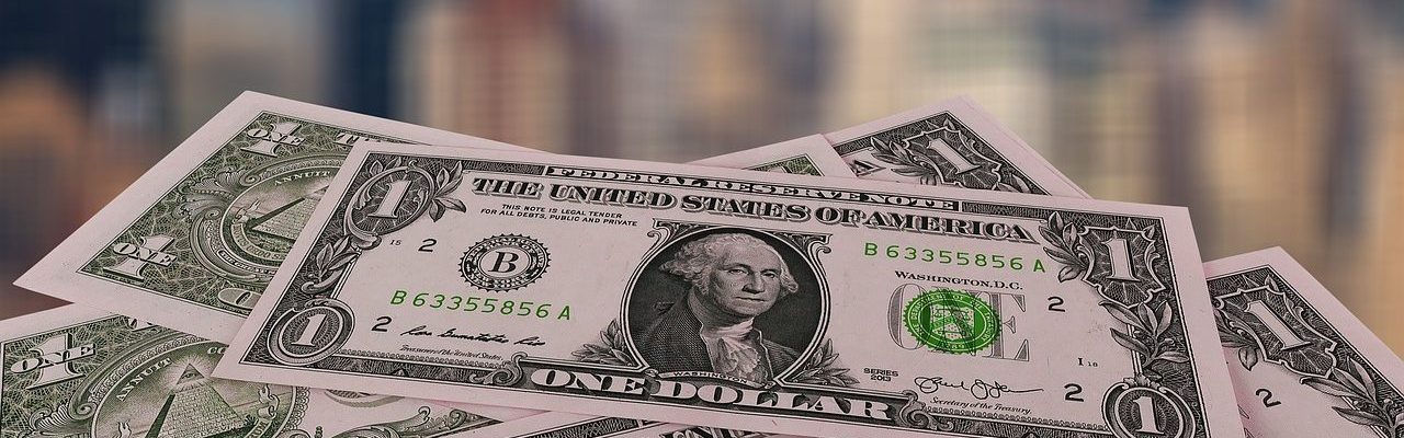 US dollar bills atop with cityscape background, representing finance and economy in urban settings